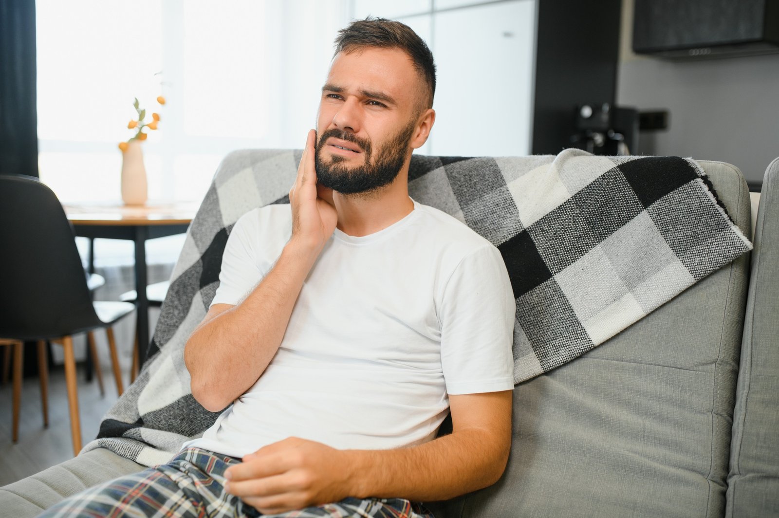 Man with sensitive teeth suffering from pain at home