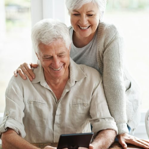 A senior couple examining a digital tablet as they sit at they dining room table